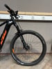 Vorderseite eines schwarzen Mountainbikes mit orangefarbenen Akzenten und Dämpfer.