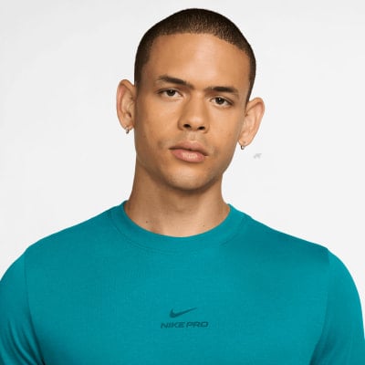 Mann in einem türkisfarbenen Nike Pro T-Shirt mit Logo auf der Brust. Mann in einem türkisfarbenen Nike Pro T-Shirt mit Logo auf der Brust.