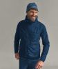 Ein Mann in einer dunkelblauen Daunenjacke und Mütze lächelt.