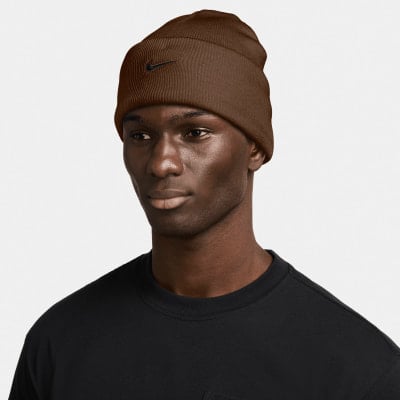 Ein Mann in einer braunen Nike-Mütze und einem schwarzen T-Shirt vor weißem Hintergrund. Ein Mann in einer braunen Nike-Mütze und einem schwarzen T-Shirt vor weißem Hintergrund.