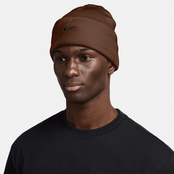 Ein Mann in einer braunen Nike-Mütze und einem schwarzen T-Shirt vor weißem Hintergrund.