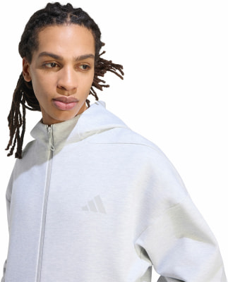 Ein Mann mit Dreadlocks in einem grauen Hoodie mit Adidas-Logo vor weißem Hintergrund. Ein Mann mit Dreadlocks in einem grauen Hoodie mit Adidas-Logo vor weißem Hintergrund.