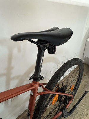 Ein rotes Fahrrad mit schwarzem Sattel und Hinterrad.