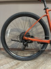 Hinterrad eines orangefarbenen Fahrrads mit Kassette und Schaltwerk.
