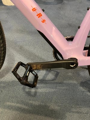 Rosa Fahrradrahmen mit orangefarbenem URS-Schriftzug und schwarzem Pedal. Rosa Fahrradrahmen mit orangefarbenem URS-Schriftzug und schwarzem Pedal.