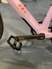 Rosa Fahrradrahmen mit orangefarbenem URS-Schriftzug und schwarzem Pedal.