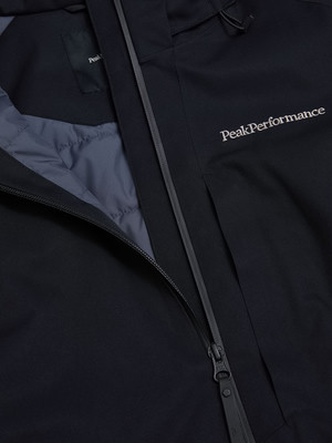 Detail einer schwarzen Jacke mit Peak Performance Logo und Reißverschluss.
