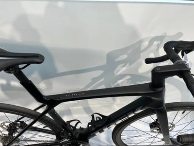 Ein schwarzes Rennrad mit tropfenförmigem Rahmen und Schattenwurf an der Wand.
