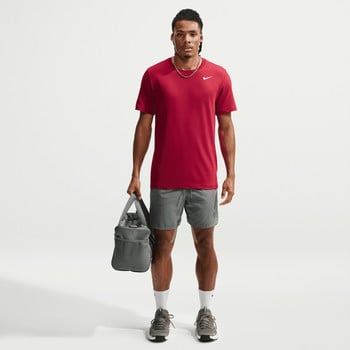 Ein Mann im roten T-Shirt und grauer Hose hält eine Tasche.