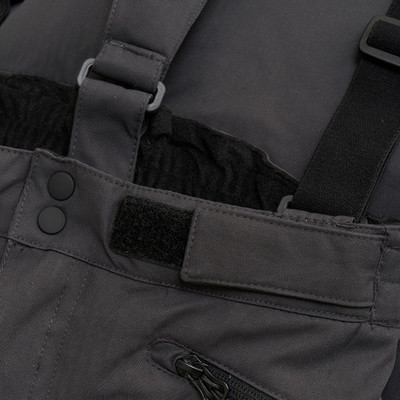 Detail einer Skihose mit Latz, Knopf- und Klettverschluss.