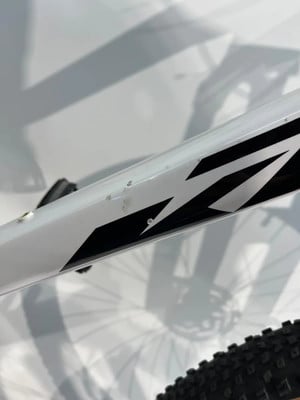 Rahmendetail eines weißen Fahrrads mit schwarzem Grafikmuster und Schatten. Rahmendetail eines weißen Fahrrads mit schwarzem Grafikmuster und Schatten.
