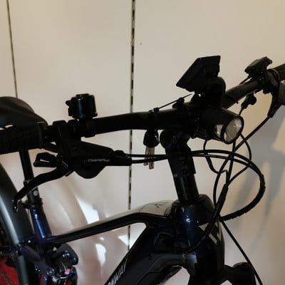Lenker eines dunkelblauen E-Bikes mit Bremshebeln und Licht. Lenker eines dunkelblauen E-Bikes mit Bremshebeln und Licht.