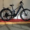 Ein blaues Conway E-Bike mit Gepäckträger und Federung in Innenräumen.