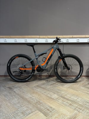 Graues KTM E-Bike mit orangefarbenen Details steht auf Holzboden. Graues KTM E-Bike mit orangefarbenen Details steht auf Holzboden.