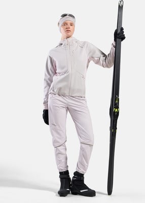 Eine Frau in Skibekleidung hält Skier und steht vor weißem Hintergrund. Eine Frau in Skibekleidung hält Skier und steht vor weißem Hintergrund.