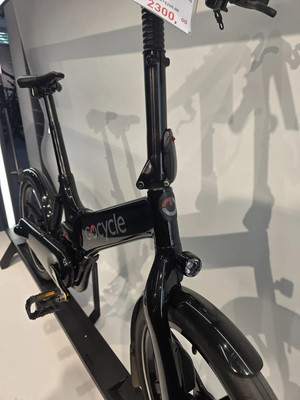 Schwarzes faltbares GoCycle-Fahrrad auf einem Display mit Preisschild. Schwarzes faltbares GoCycle-Fahrrad auf einem Display mit Preisschild.