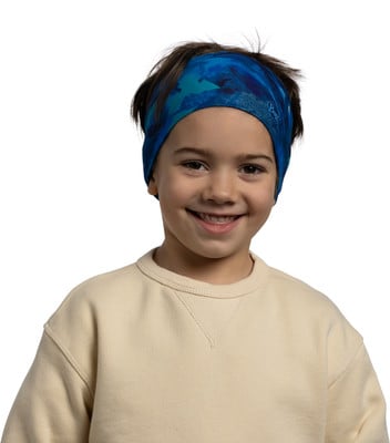 Ein Junge mit blauem Stirnband und beigefarbenem Pullover lächelt. Ein Junge mit blauem Stirnband und beigefarbenem Pullover lächelt.