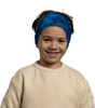 Ein Junge mit blauem Stirnband und beigefarbenem Pullover lächelt.