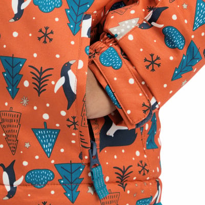 Eine geschlossene Tasche an einer Jacke mit Pinguin- und Weihnachtsbaumdruck. Eine geschlossene Tasche an einer Jacke mit Pinguin- und Weihnachtsbaumdruck.