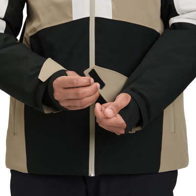 Ein Mann schließt Klettverschluss am Ärmel einer mehrfarbigen Jacke.