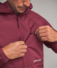 Ein Mann schließt eine Kapuzenjacke, die eine Brusttasche mit Reißverschluss hat.