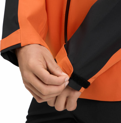 Eine Hand passt den Klettverschluss an einer orange-schwarzen Jacke an. Eine Hand passt den Klettverschluss an einer orange-schwarzen Jacke an.