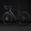 Schwarzes Carbon-Rennrad mit Scheibenbremsen auf schwarzem Hintergrund.