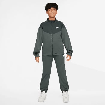 Junge im dunkelgrauen Nike Trainingsanzug mit Logo auf Brust und Bein.