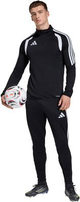 Ein Mann in schwarzer Sportkleidung hält einen Fußball.
