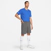 Ein Mann in einem blauen T-Shirt und grauen Shorts steht mit der Hand in der Hüfte.