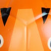 Detail eines orangefarbenen Kürbisses mit Wassertropfen und schwarzen Dreiecken.