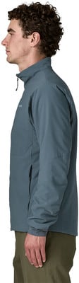 Ein Mann in einer dunkelblauen Jacke und grünen Hose steht im Profil.