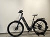 Graues E-Mountainbike mit Schutzblechen und Gepäckträger auf Ständer.