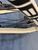 Ein weißes Fahrrad mit schwarzen Schriftzügen und Kette auf blauem Hintergrund.