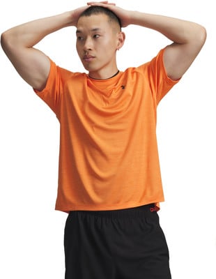 Ein Mann im orangefarbenen Hemd und schwarzer Hose hält die Hände über dem Kopf. Ein Mann im orangefarbenen Hemd und schwarzer Hose hält die Hände über dem Kopf.