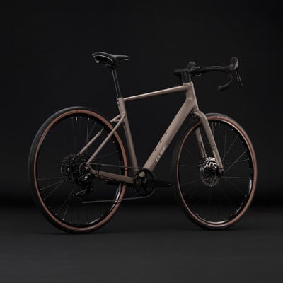 Ein braunes Cube Gravelbike mit schwarzen Felgen und Lenkern vor dunklem Hintergrund. Ein braunes Cube Gravelbike mit schwarzen Felgen und Lenkern vor dunklem Hintergrund.