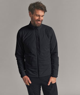 Ein Mann in einer schwarzen Jacke und Hose lächelt und blickt nach unten. Ein Mann in einer schwarzen Jacke und Hose lächelt und blickt nach unten.