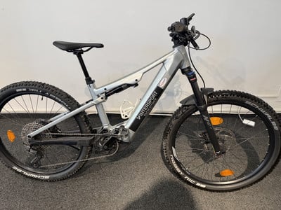 Silbernes E-Bike mit Federung und breiten Reifen auf dunklem Untergrund. Silbernes E-Bike mit Federung und breiten Reifen auf dunklem Untergrund.
