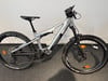 Silbernes E-Bike mit Federung und breiten Reifen auf dunklem Untergrund.