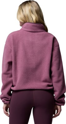 Rückansicht einer Frau in einem rosafarbenen Fleece-Pullover und lila Leggings.