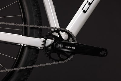 Detail eines weißen Fahrrads mit Kette und Shimano-Kurbeln.