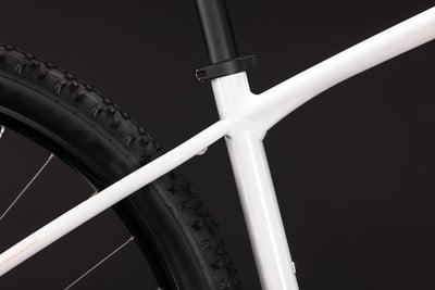 Detail eines weißen Mountainbike-Rahmens mit schwarzem Reifen.