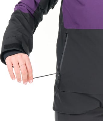 Eine Frau schließt mit der Hand einen Reißverschluss an einer Jacke, sie trägt einen Ring.
