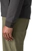 Detail einer Hand und eines Ärmels einer dunklen Jacke über grünen Hosen.