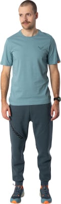 Ein Mann in einem blauen T-Shirt und dunkler Hose mit Dynafit-Logo. Ein Mann in einem blauen T-Shirt und dunkler Hose mit Dynafit-Logo.