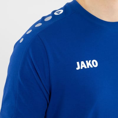 Blaues JAKO T-Shirt mit weißem Logo und Punkten auf den Schultern. Blaues JAKO T-Shirt mit weißem Logo und Punkten auf den Schultern.