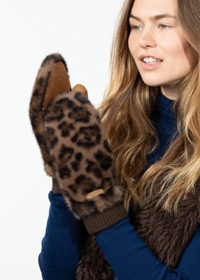 Eine junge Frau mit langen blonden Haaren trägt leopardfarbene Fäustlinge und einen blauen Pullover. Eine junge Frau mit langen blonden Haaren trägt leopardfarbene Fäustlinge und einen blauen Pullover.