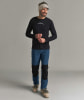 Ein Mann in einem schwarzen Langarmshirt und blauen Hosen mit schwarzen Einsätzen.