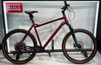 Ein Fahrrad mit einem weinroten Rahmen und braunen Rädern auf einem Ständer.