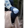 Detail einer Hand in einem gestrickten Handschuh und einer Teddyfelljacke.